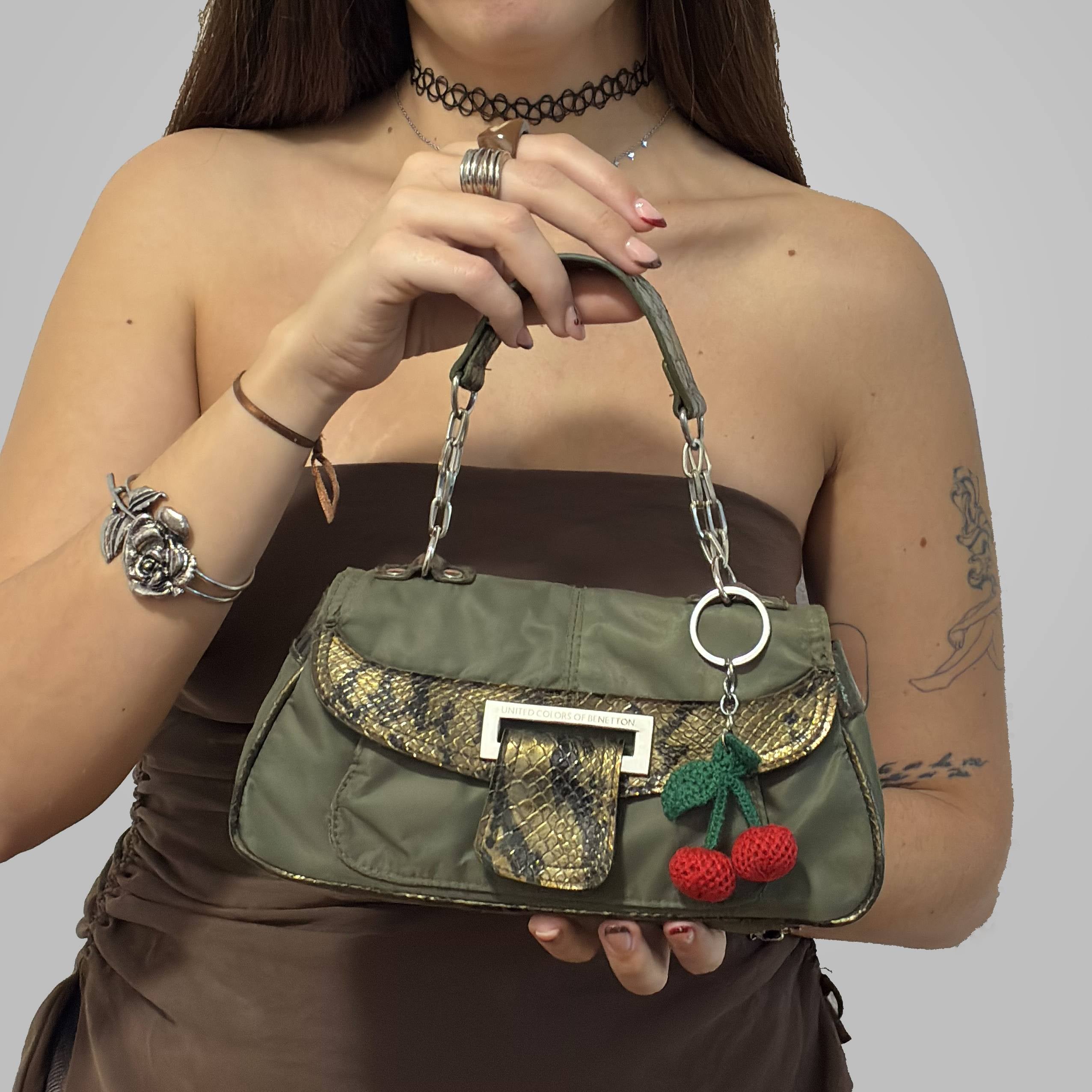 Bolso Benetton Python Khaki con detalles en imitación de piel de serpiente y charm de cerezas. Bolso Benetton Python Khaki con detalles en imitación de piel de serpiente y charm de cerezas.